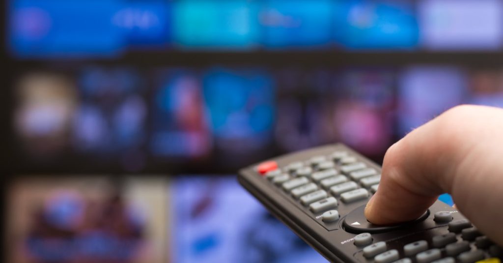man holding a remote in front of tv
